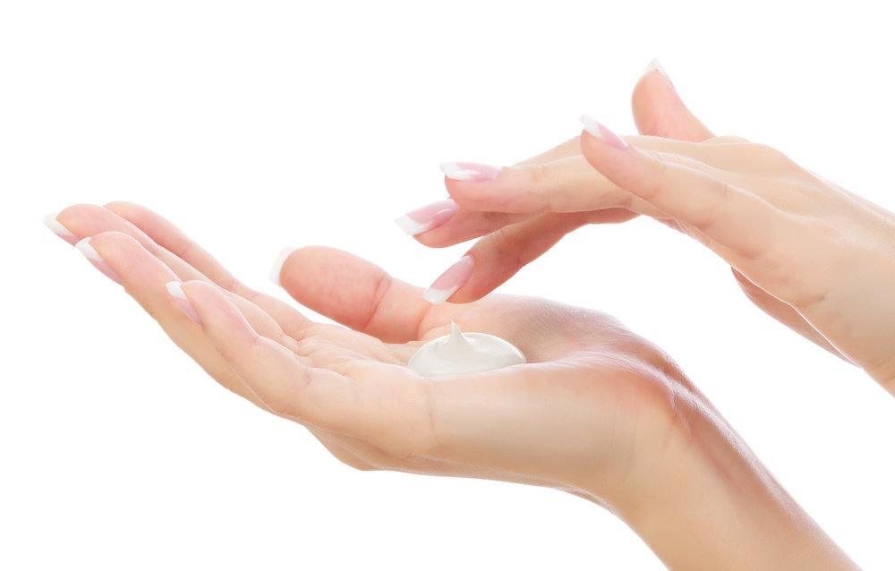 Close-up of a woman’s hands with fingers dipping a small amount of the product from her hand.