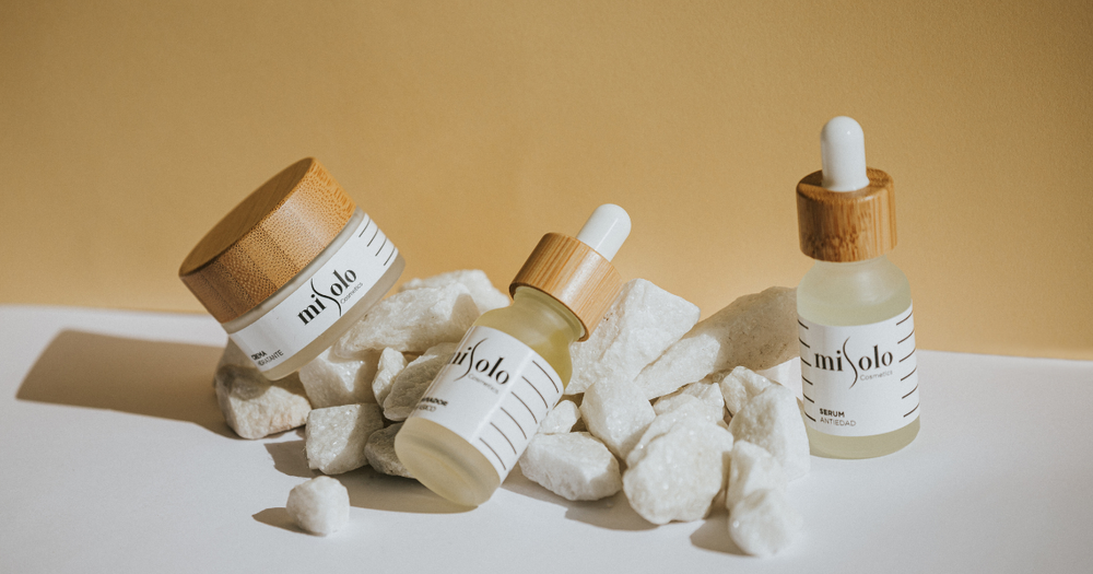 Beauty and skin care products staged with white rocks on a white table with a gold background